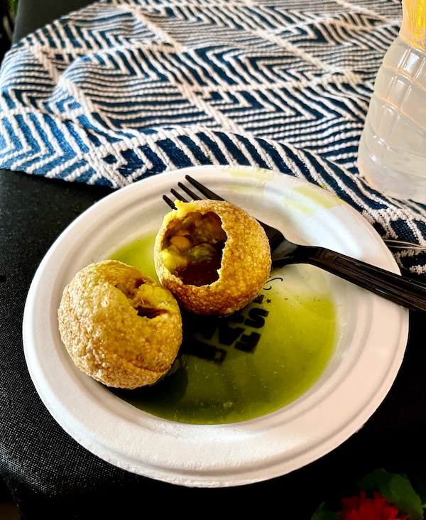 White plate with hollowed balls filled with brown meat with green sauce on plate at Family Style FoodFest NOLA