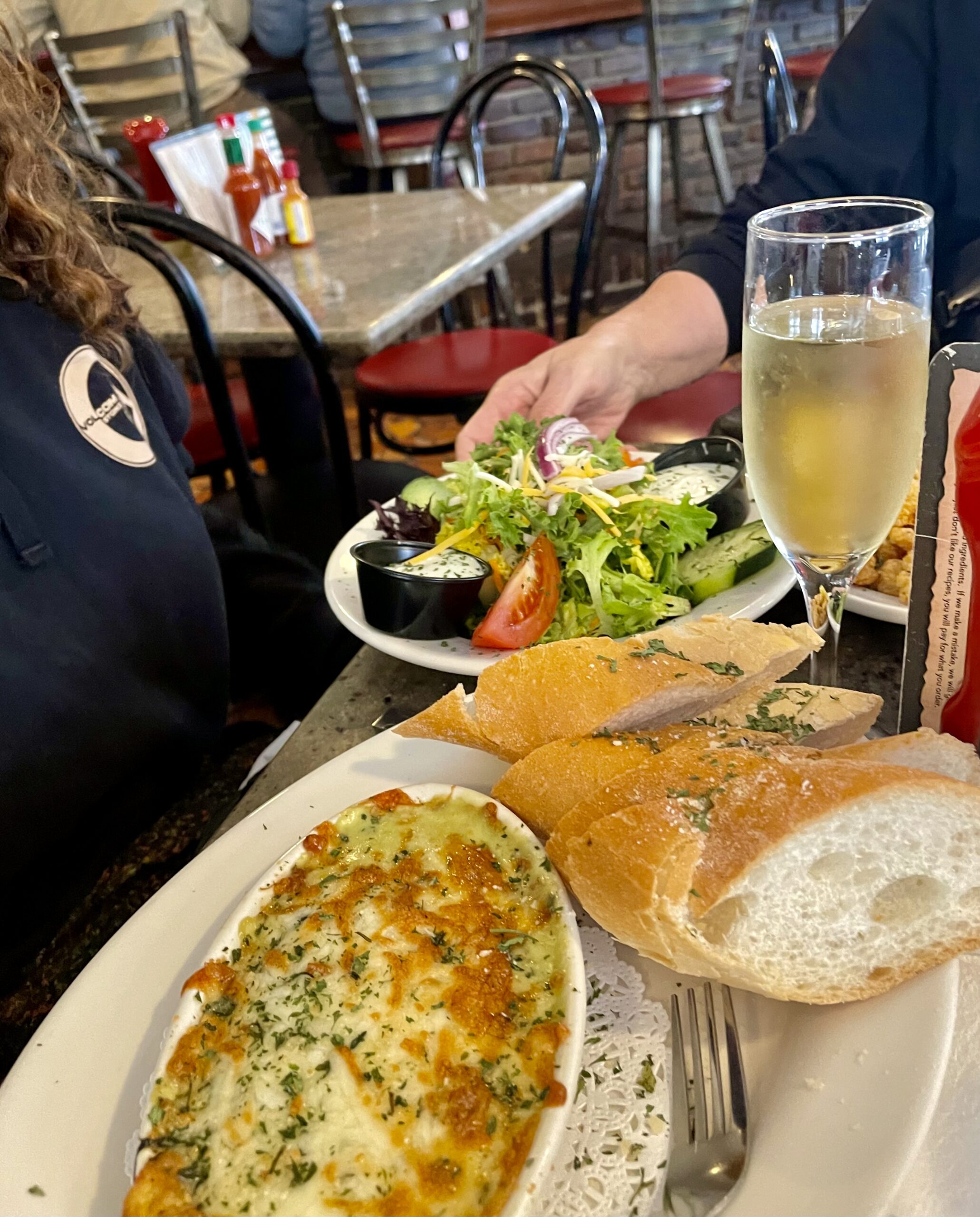 Partial view of our gratin with bread slices, large plate of salad and a flute of champagne