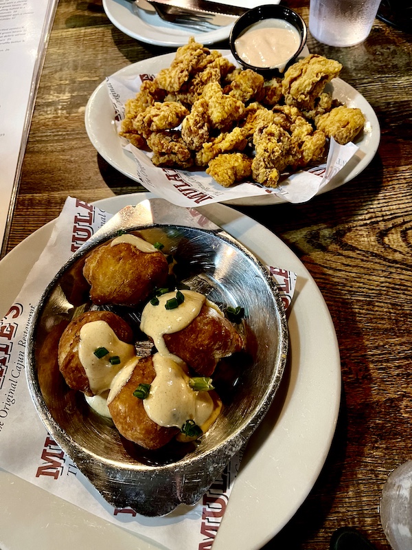 Mulate's the Original Cajun Restaurant's Crab filled puffs topped with pink sauce in foreground. Behind is a plate of fried oysters with sauce.