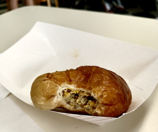 One of our Delicious Texas Kolaches with a bite out of it sitting in a white cardboard dish.