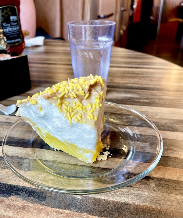 Clear glass plate topped with a slice of lemon meringue pie at House of Pies Houston Texas