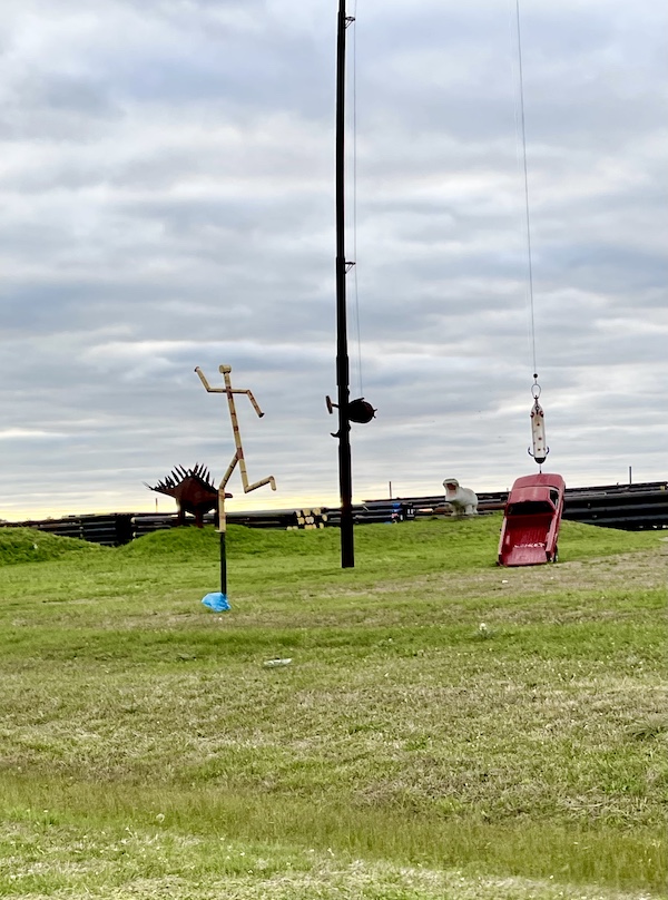 Red pick up truck hooked on a lure of a fishing rod with other metal sculptures on the lawn are part of the Roadside Art in Houston Texas