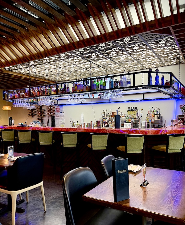 Beautiful well lit bar at Thaicoon Restaurant Pearland Texas with lots of bottles of wine and spirits on display.