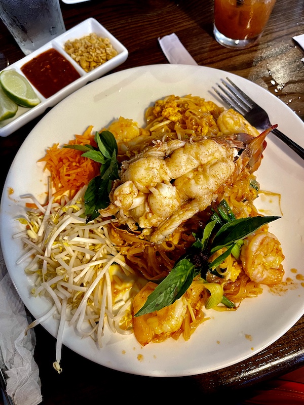 White plate topped with noodles, matchstick carrots, bean sprouts, basil leaves, chopped nuts and lobster tail at Thaicoon Restaurant Pearland Texas