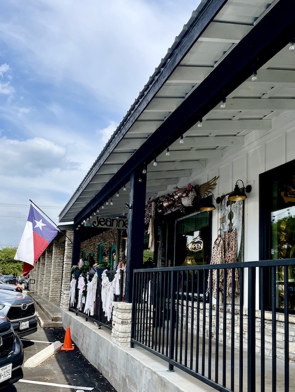 Row of shop storefronts and a Texas state flag flying in Hill Country's Wimberley Texas
