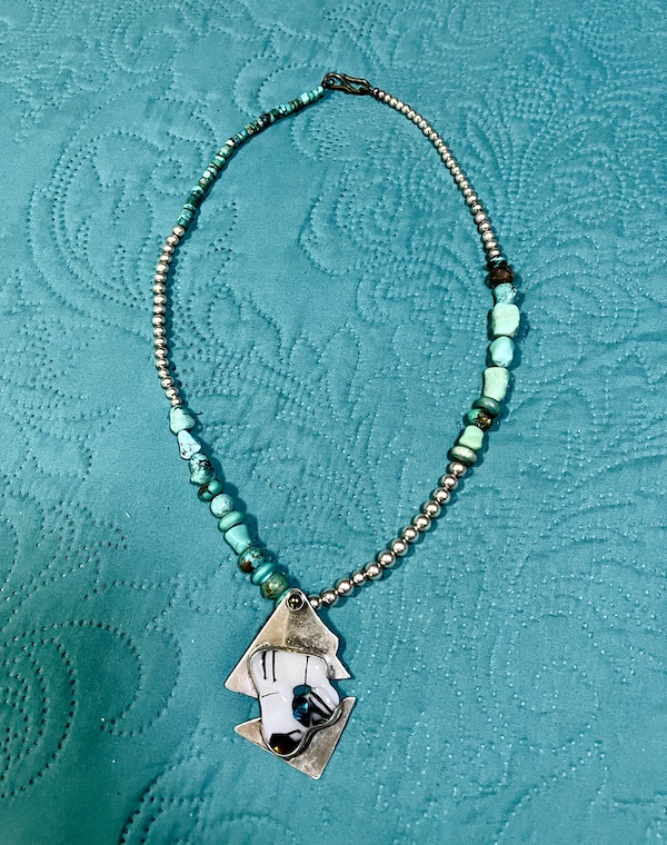 Turquoise and silver necklace with silver and art glass pendant on a turquoise background