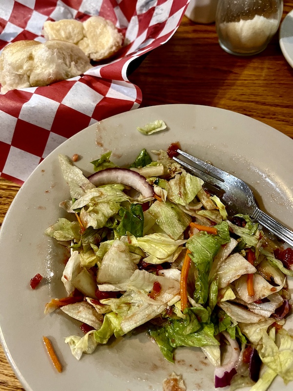 Shallow bowl filled with dressed salad, bread basket in background at Italian Garden Restaurant Canyon Lake TX