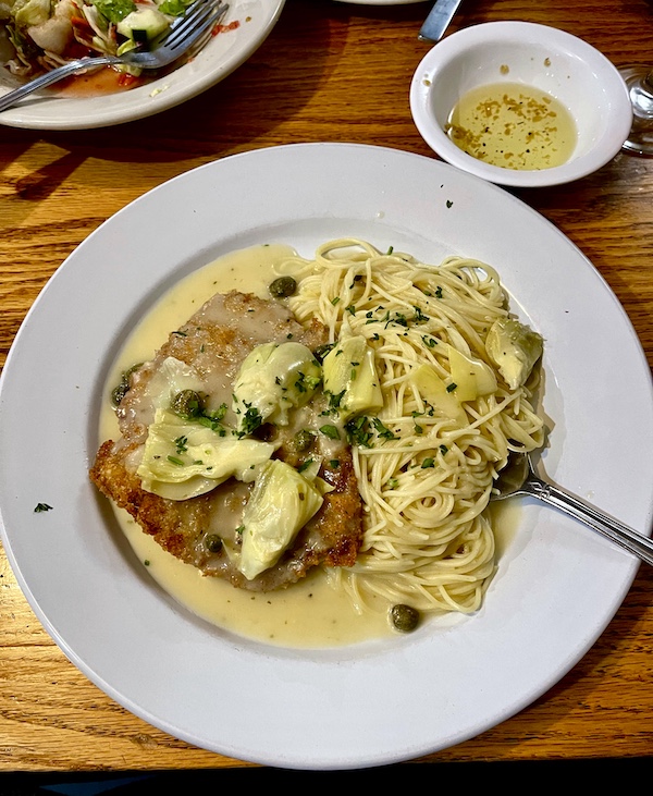 Plate topped with crusted veal, lemon butter sauce, capers, artichoke hearts and linguine at Italian Garden Restaurant Canyon Lake TX