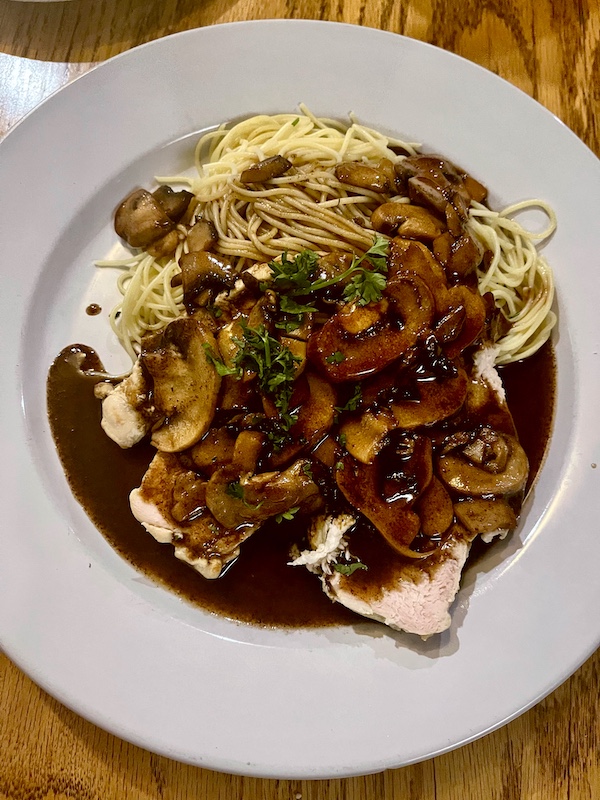 Plate topped with veal, mushrooms, linguine, brown sauce and parsley at Italian Garden Restaurant Canyon Lake TX