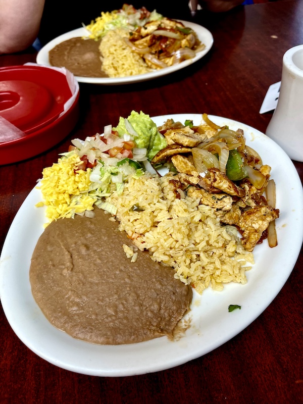 White plate topped with chicken, salad, corn, rice and refried beans at Monterrey Café New Braunfels TX