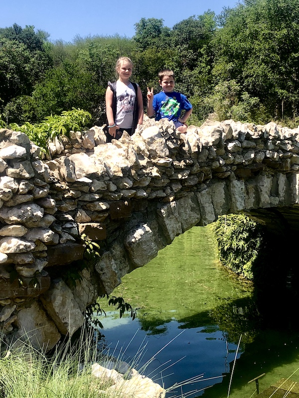Boy and girl on limestone bridge over water at the Japanese Tea Garden San Antonio