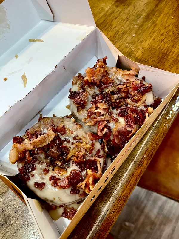 Open box holding 2 maple bacon donuts enjoyed before visiting the Japanese Tea Garden San Antonio