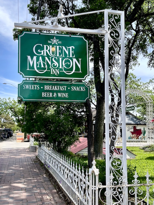 Green sign with white lettering Gruene Mansion in New Braunfels and Gruene Texas