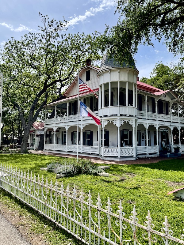 Side view of white Inn with ornate railings on the porches and balconies in New Braunfels and Gruene Texas