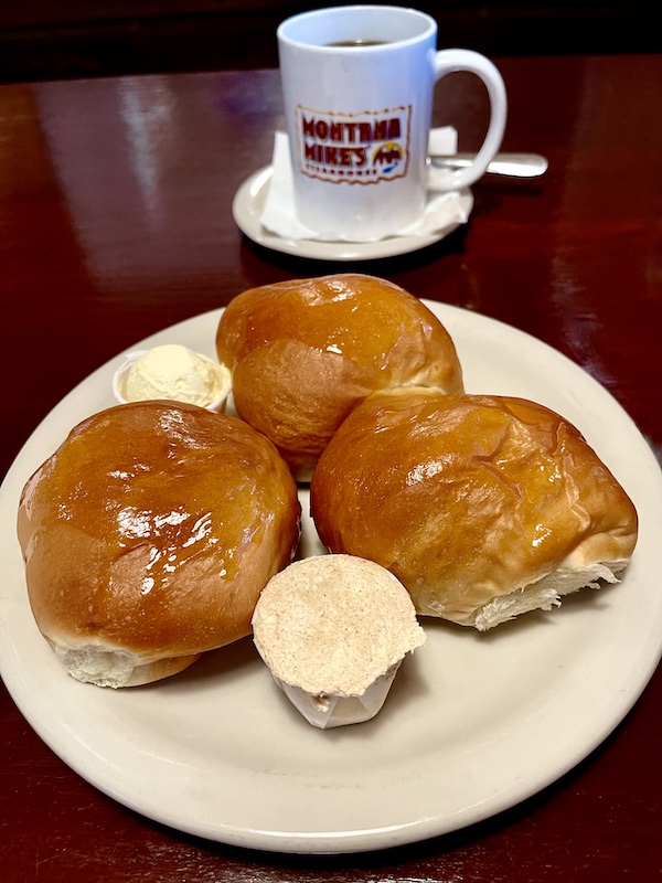 Plate of 3 glazed rolls and butter on wood table in restaurant in New Braunfels and Gruene Texas