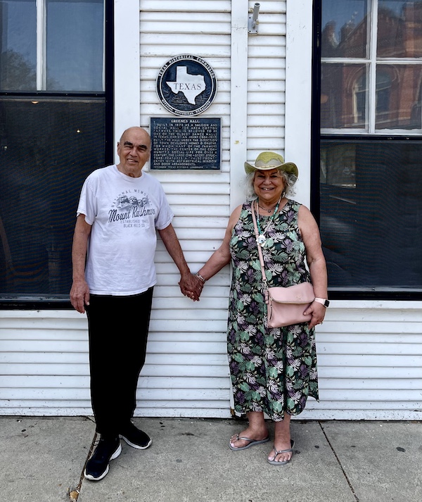 Steve and I holding hands in front of a white clapboard building that's Gruene Hall.