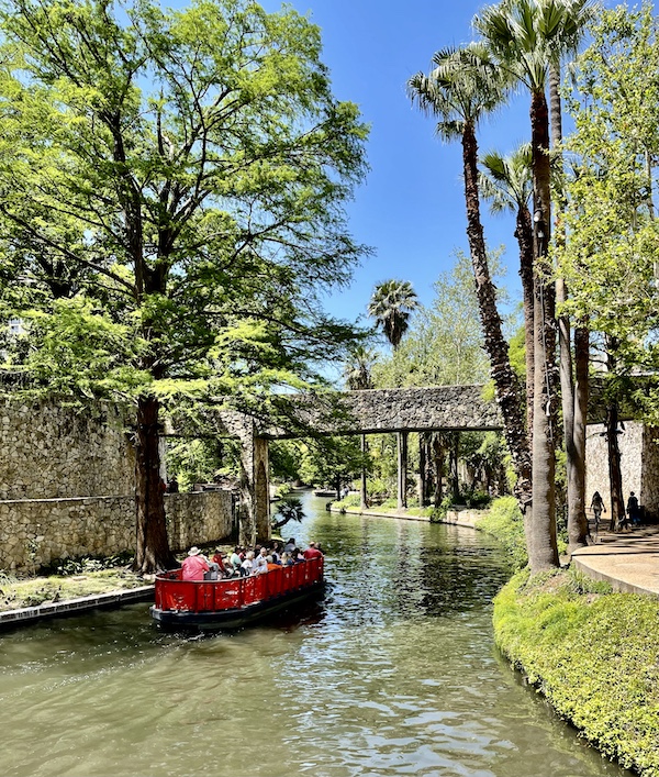 Red river boat cruising filled with tourists on board at the San Antonio River Walk