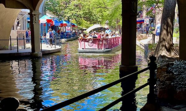 Colorful river boats cruise under the bridge at San Antonio River Walk