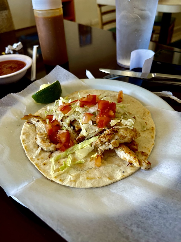 White plate topped with large taco filled with chicken, tomatoes, lettuce and lime for breakfast before our Sunday Funday Fredericksburg Texas