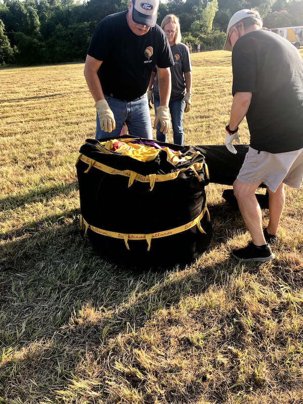 Black bag with yellow strap with men about to empty it on a grass field at the Hopkins County Dairy Festival 2025
