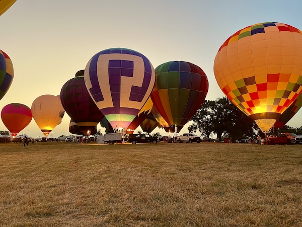 Large group of hot air balloons aglow on a field at the Hopkins County Dairy Festival 2025