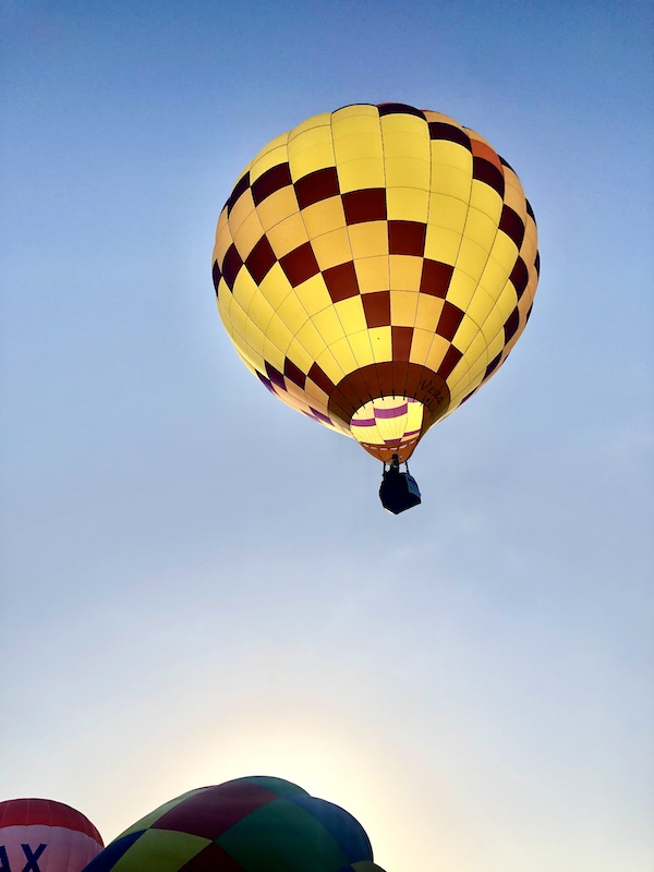 Yellow, orange and burgundy hot air balloon soaring in the sky at the Hopkins County Dairy Festival 2025