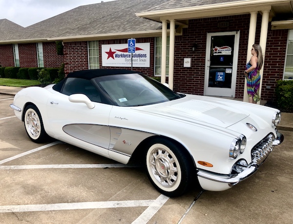 White custom Corvette with black soft top in front of a brown building at the Hopkins County Dairy Festival 2025