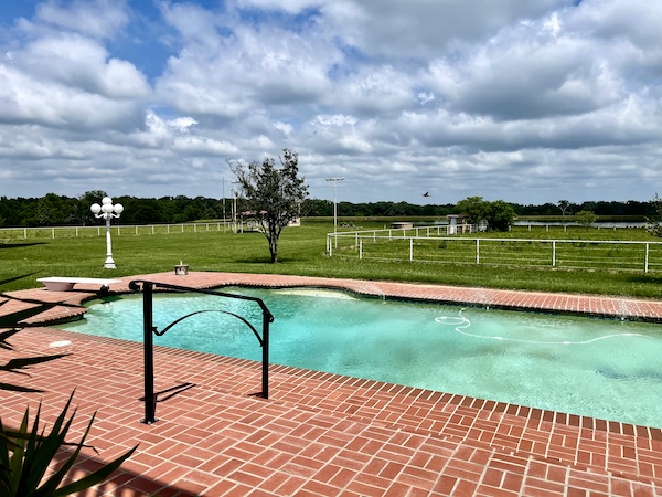 June Fun in Sulphur Springs TX including enjoying their pool with red brick pavers and pastures surrounding it.