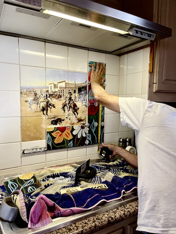 Steve placing colorful flower tiles over a cowboy theme mosaic as part of the Kitchen Transformation in Texas