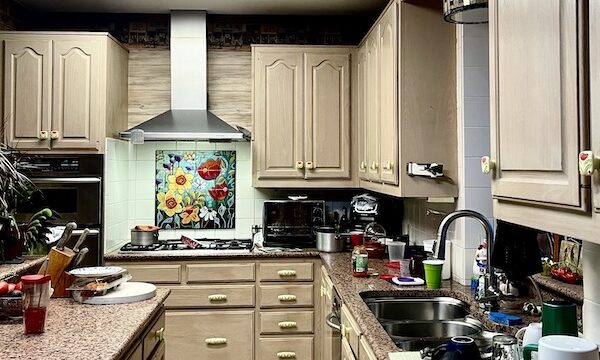 View of kitchen with new mosaic above stove, beige wood cabinets and new handles during the Kitchen Transformation in Texas