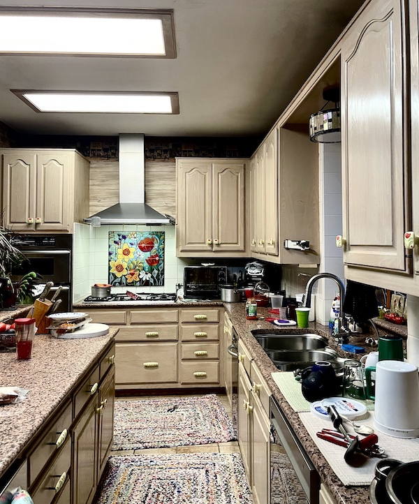 View of kitchen with new mosaic above stove, beige wood cabinets and new handles during the Kitchen Transformation in Texas
