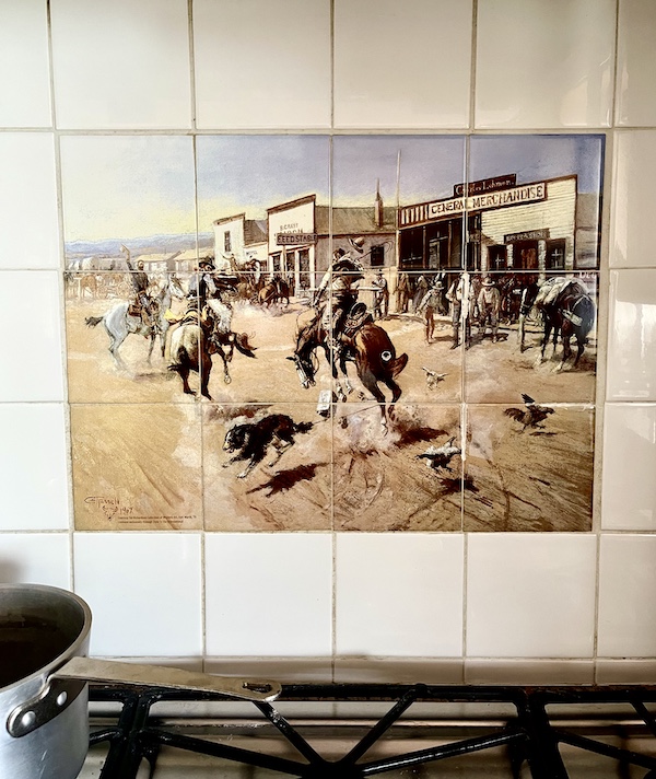 Monotone cowboy themed tile mosaic backsplash above stove prior to the Kitchen Transformation in Texas