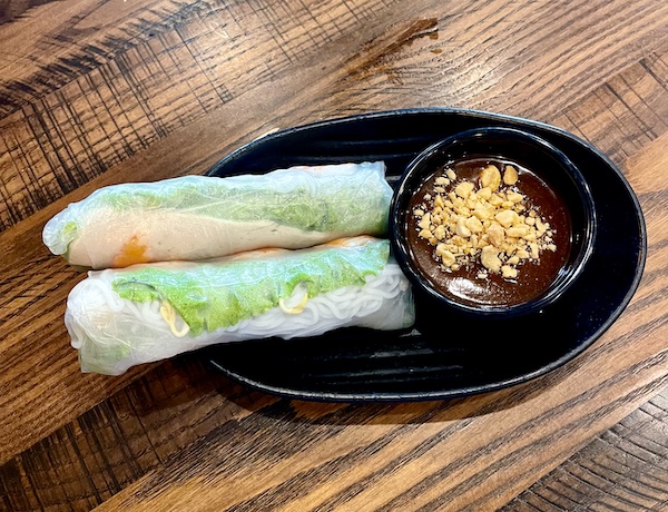 Black plate topped with 2 spring rolls and a small bowl of sauce with crushed peanuts on top was part of our Taste Vietnam in Houston TX