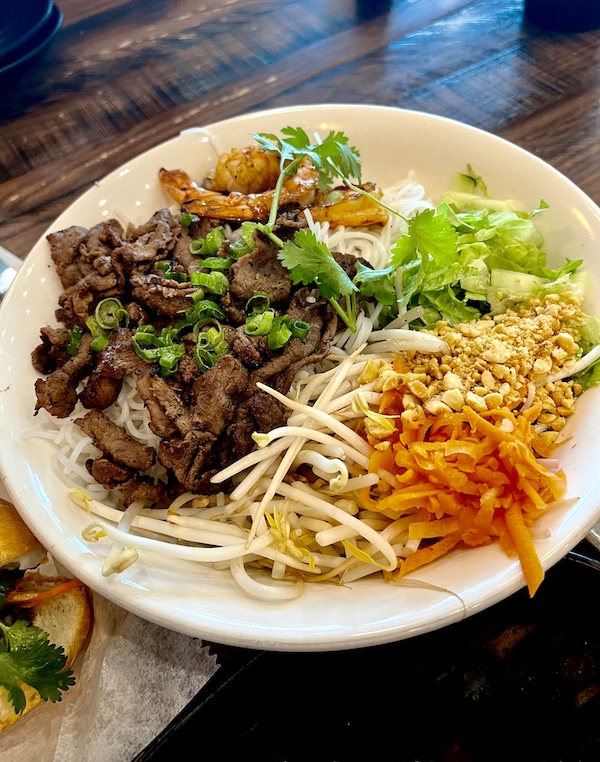 Large white bowl filled with sliced beef, grilled shrimp, cilantro, shredded carrots, thin noodles, bean sprouts and chopped peanuts was a Taste Vietnam in Houston TX