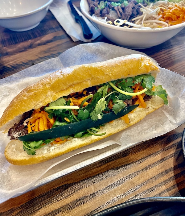 Rectangular white plate topped with a hero roll filled with sliced pork, carrots, radish and cucumber was a Taste Vietnam in Houston TX