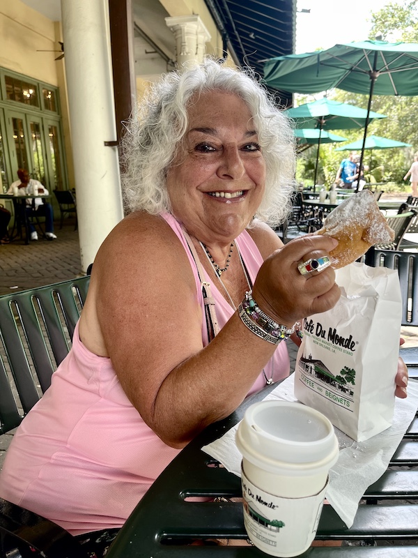 Me at a table about to take a bite of a powdered sugar coated beignet during our Bonus Visit to NOLA