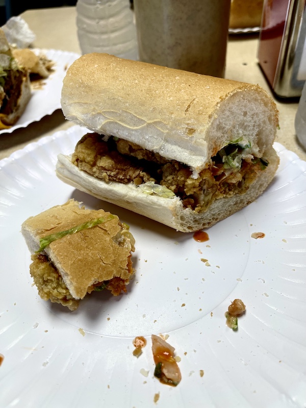 White plate with half an oyster po' boy plus a tiny portion of the first half enjoyed during our Bonus Visit to NOLA
