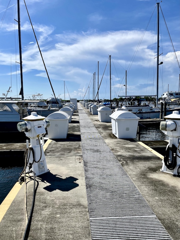 Long concrete pier at a marina with white lockers and sailboat masts visited during our Bonus Visit to NOLA