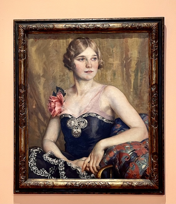 Painting of a woman seated in a chair wearing a black gown with rose on one shoulder at the Westmoreland Museum of American Art