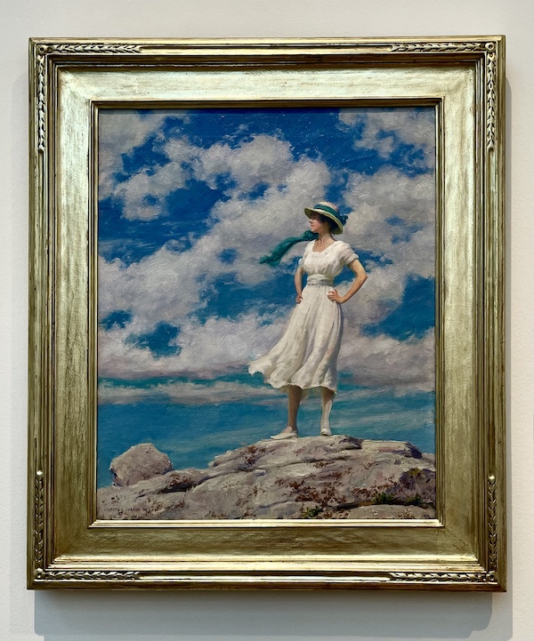 Painting of a woman in white dress standing on rocks by the water with blue sky and lots of puffy white clouds at Westmoreland Museum of American Art