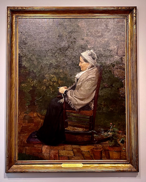 Portrait of an old woman sitting in a chair knitting at the Westmoreland Museum of American Art