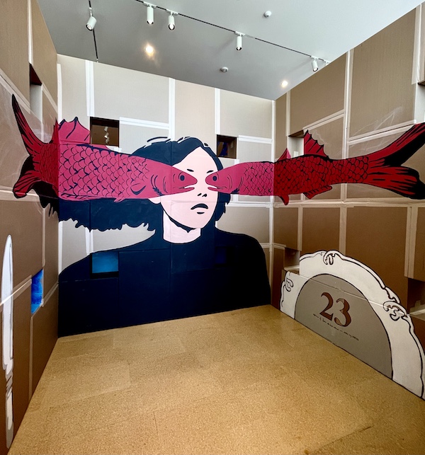 Mural of a woman in navy with magenta fish covering her eyes painted on cardboard at Westmoreland Museum of American Art 2