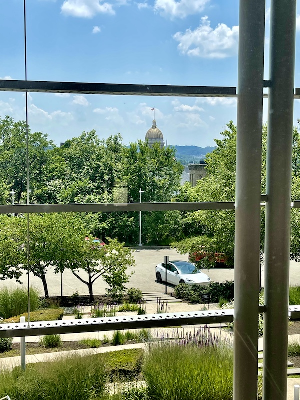 View of the Westmoreland Museum of American Art grounds, parking lot and mountains through glass window.