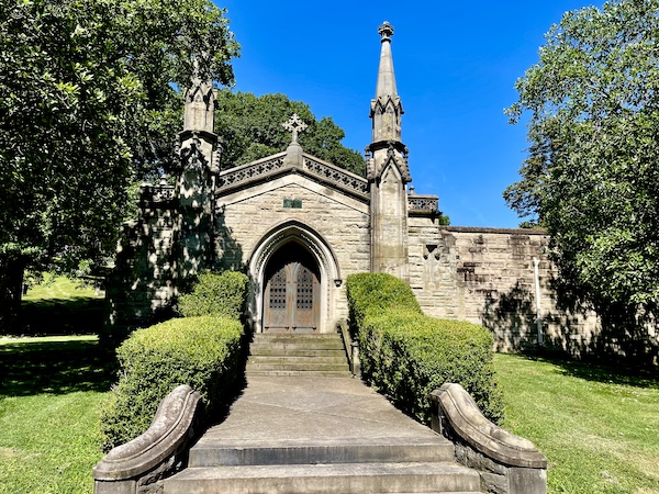 Huge stone Gothic style mausoleum with many steps leading to the door and bushes lining the steps at Allegheny Cemetery Pittsburgh Pennsylvania