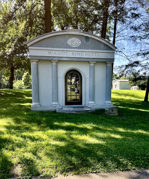 Gray mausoleum with columns and arched door with glass panes at Allegheny Cemetery Pittsburgh Pennsylvania