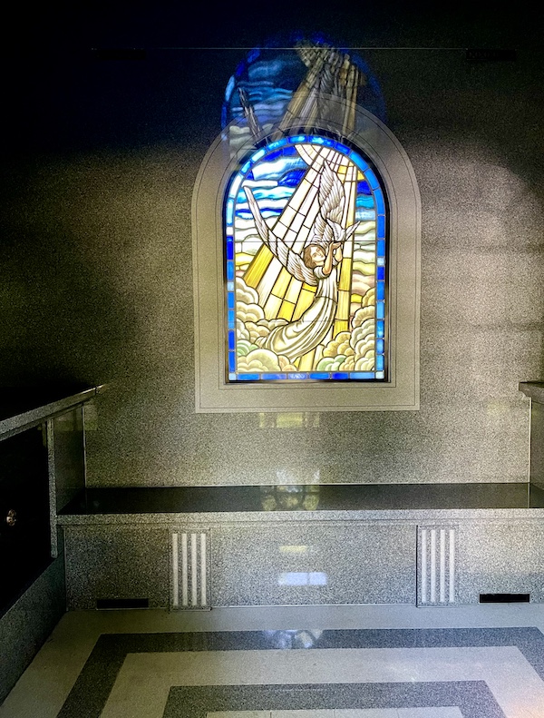 Colorful stained glass window of an angel in a ray of sunlight inside a mausoleum at Allegheny Cemetery Pittsburgh Pennsylvania