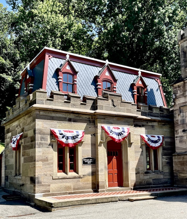 Stone carriage house with red door and red white and blue festoons at Allegheny Cemetery Pittsburgh Pennsylvania