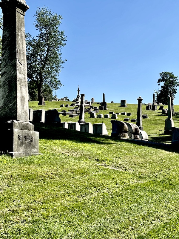 Tall and small monuments on hilly lawn with trees at Allegheny Cemetery Pittsburgh Pennsylvania