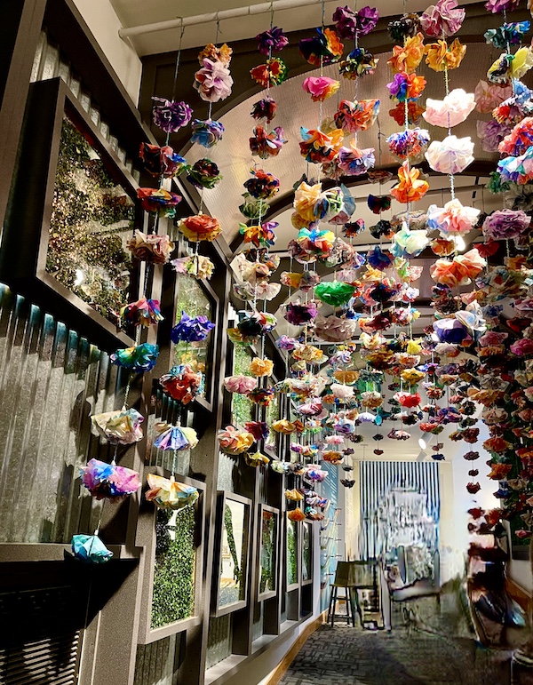 Over 500 paper flowers hang from the ceiling of a hallway at the Allentown Art Museum