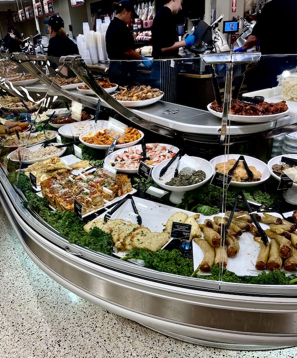 DeLallo Italian Marketplace curved case of serving dishes full of prepared foods.